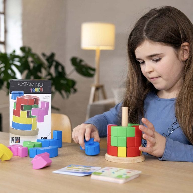 ילדה משחקת קטמינו לגובה מרכיבה מגדל צבעוני